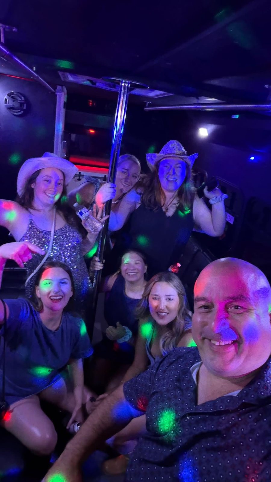 Guests celebrating under colorful party lights inside the Party Buzzed bus